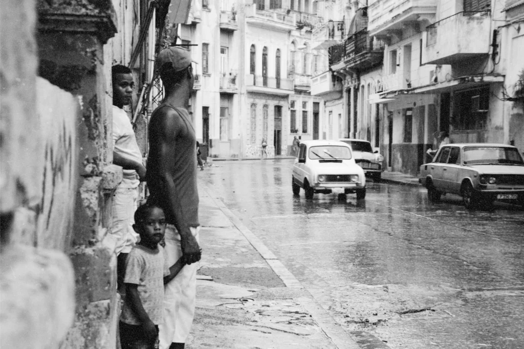 Tres hombres de distintas generaciones en la acera de una calle en el centro de La Habana, Cuba